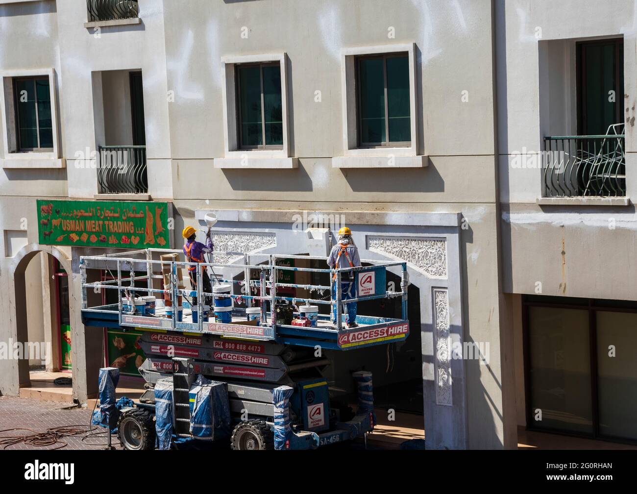 Dubai, VAE - Aufnahme eines in der Höhe arbeitenden Wartungspersonal, das die Fassade des Gebäudes im internationalen Stadtbezirk repariert. Stockfoto