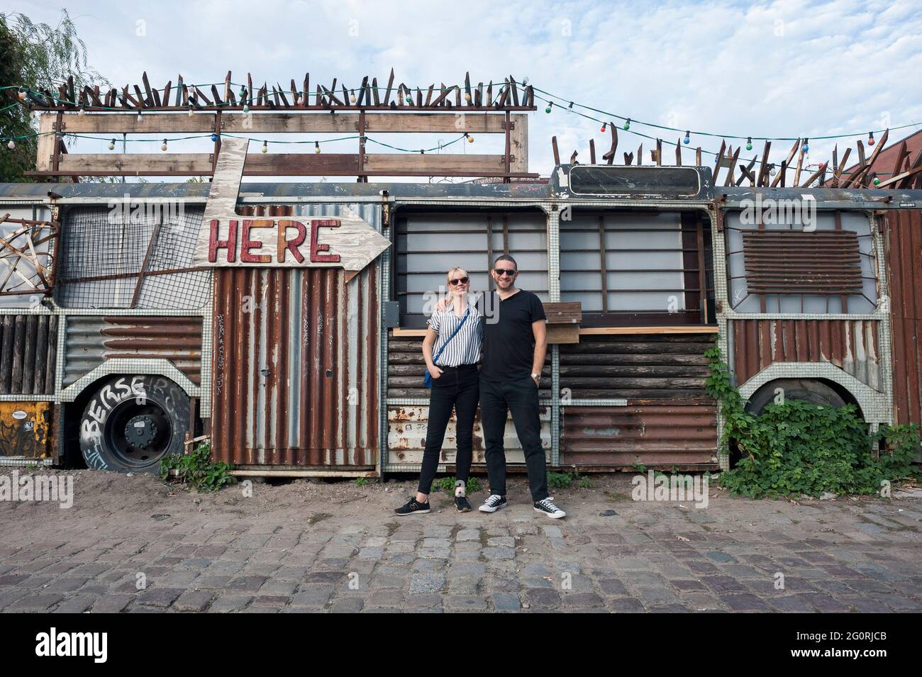 Ein Paar steht vor einem skurrilen rostigen Bus in Berlin-Deutschland auf einem romantischen Städtetrip Stockfoto