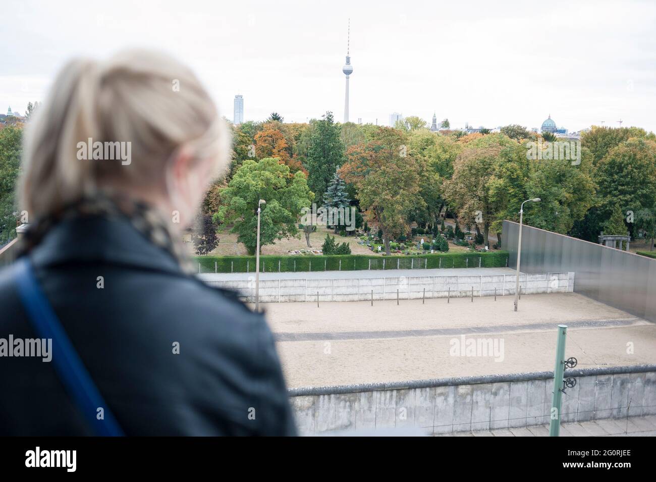 Eine echte Person, die während eines Städtereise auf die Berliner Mauer steht und schaut Stockfoto