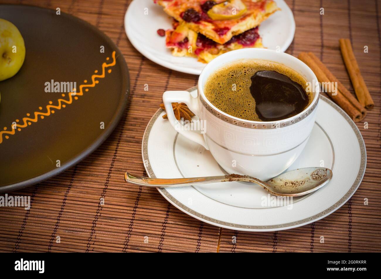 Stillleben - eine Tasse schwarzen Kaffee, hausgemachte Kekse mit Obst, gebackene Äpfel auf einer Bambusmatte Stockfoto