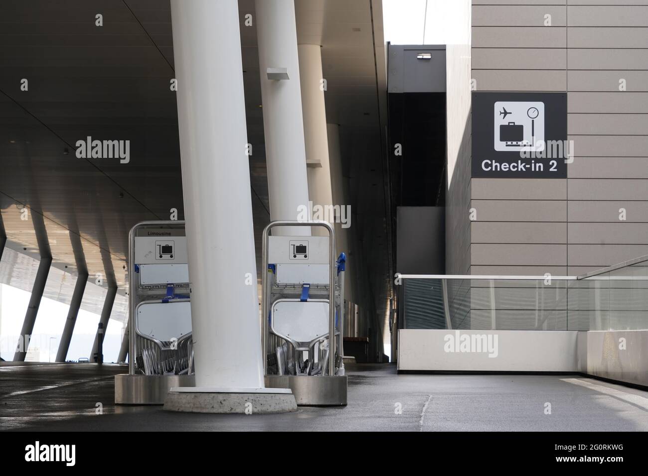 Gepäckwagen oder Gepäckwagen, die in zwei Reihen vor dem Check-in-Terminal eines Flughafens angeordnet sind. Stockfoto