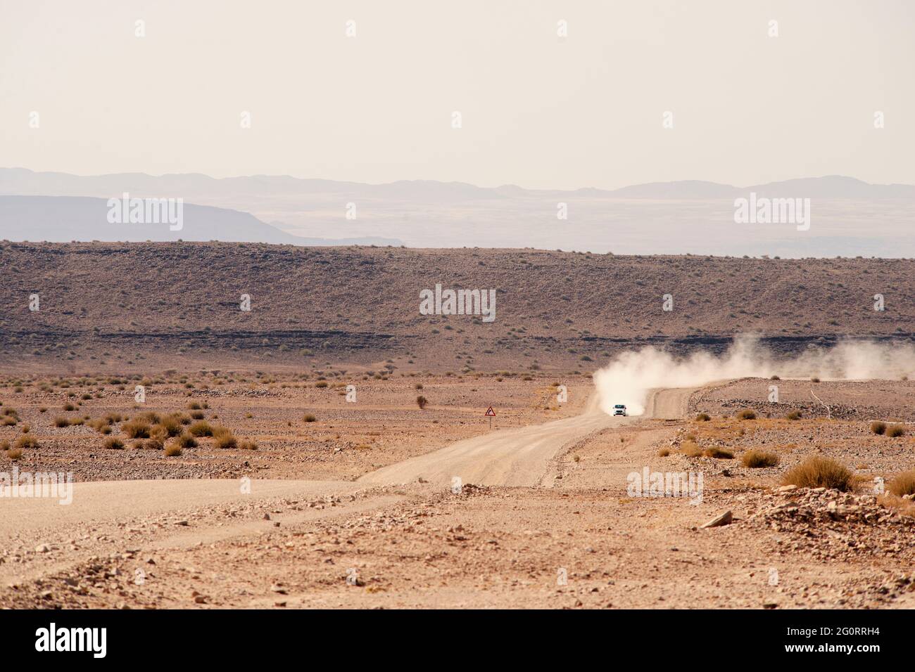 Entferntes Auto, das sich über eine Schotterstraße in der Wüste Namibias bewegt Stockfoto