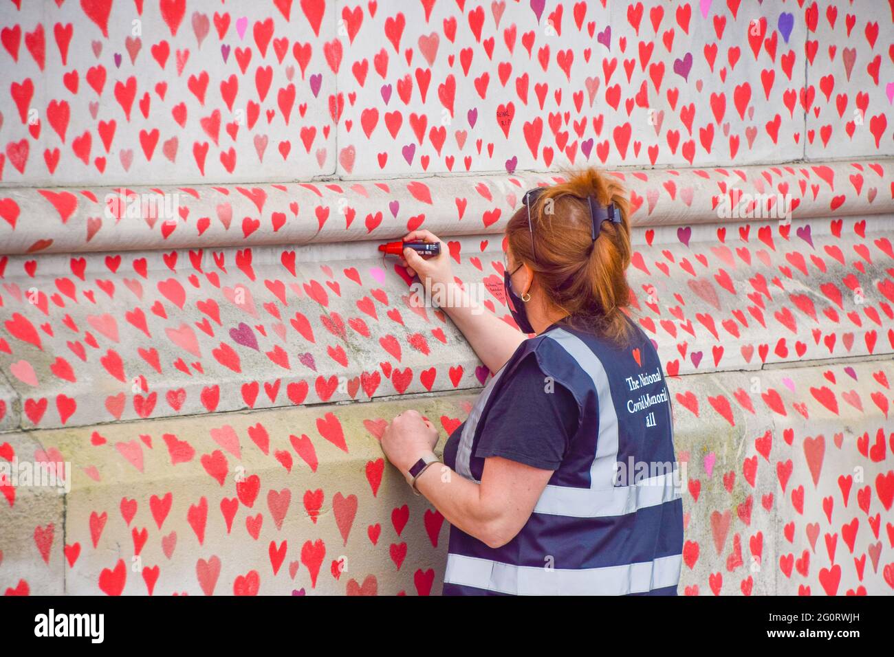 London, Großbritannien. 31st. März 2021. Ein Freiwilliger malt rote Herzen an der National Covid Memorial Wall. Fast 150.000 Herzen werden von Freiwilligen gemalt, eines für jedes Covid-19-Opfer in Großbritannien bis heute, an der Wand vor dem St. Thomas' Hospital am Südufer der Themse gegenüber dem Parlamentsgebäude. Stockfoto