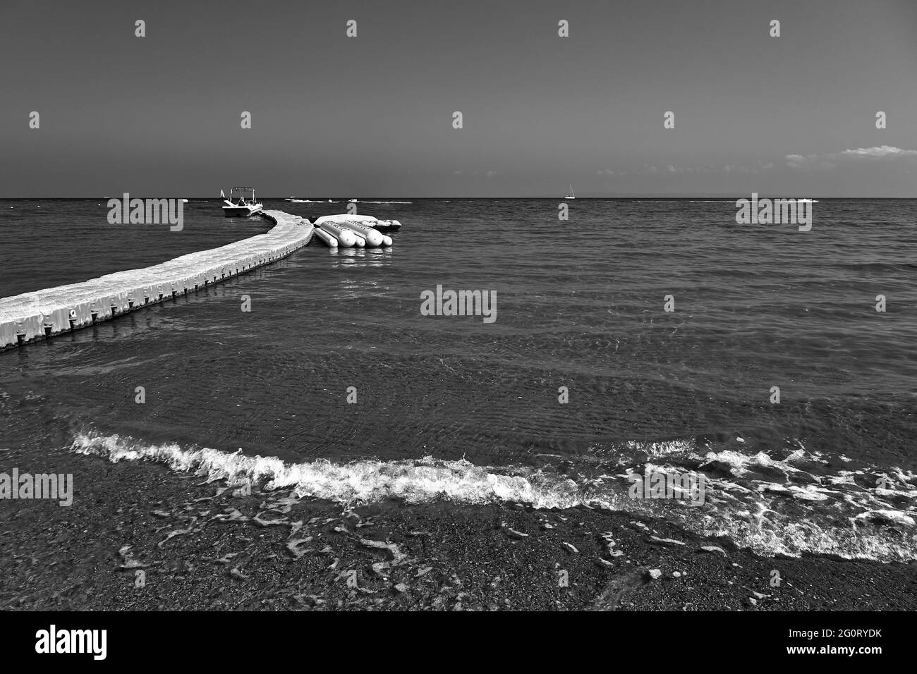 Schwimmende Anlegestelle mit einem Motorboot und Pontons am Strand auf der Insel Zakynthos in Griechenland, monochrom Stockfoto