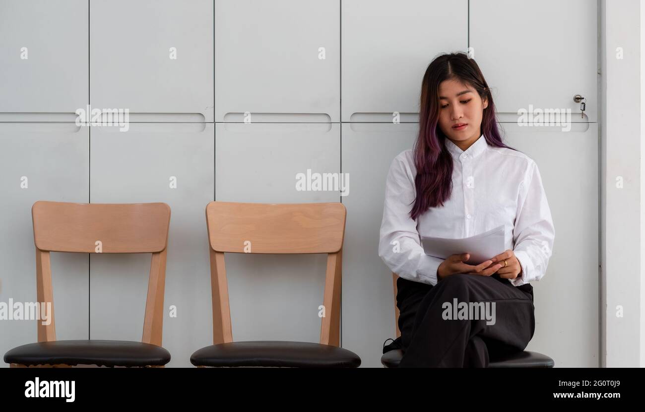 Asiatische Frau mit Lebenslauf sitzen, um die Dokumente zu überprüfen, während sie auf ein Vorstellungsgespräch wartet Stockfoto