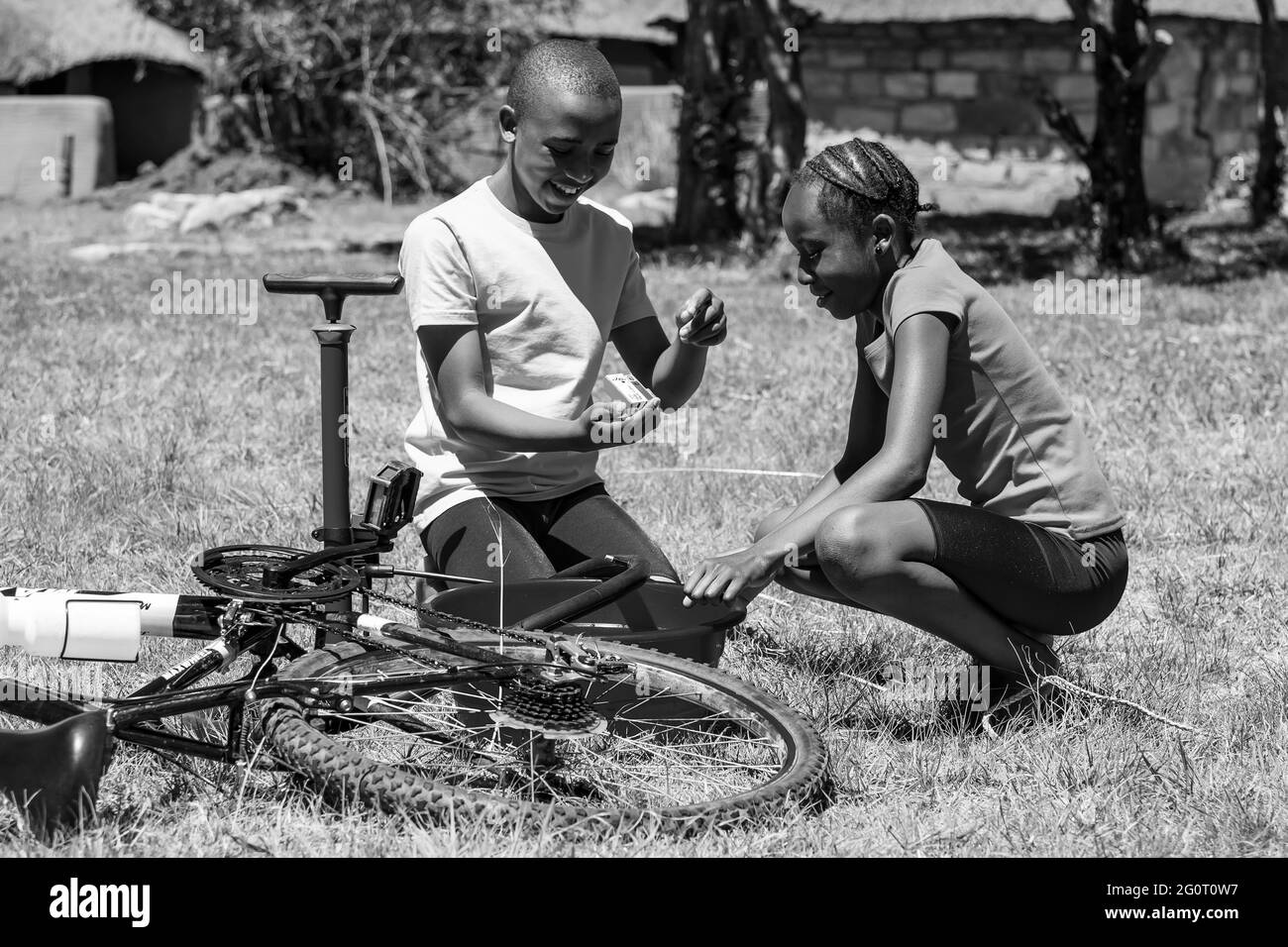 HARRISMITH, SÜDAFRIKA - 05. Jan 2021: Harrismith, Südafrika - 18 2012. Oktober: Afrikanische Kinder, die eine Punktion auf einem Fahrrad reparieren Stockfoto