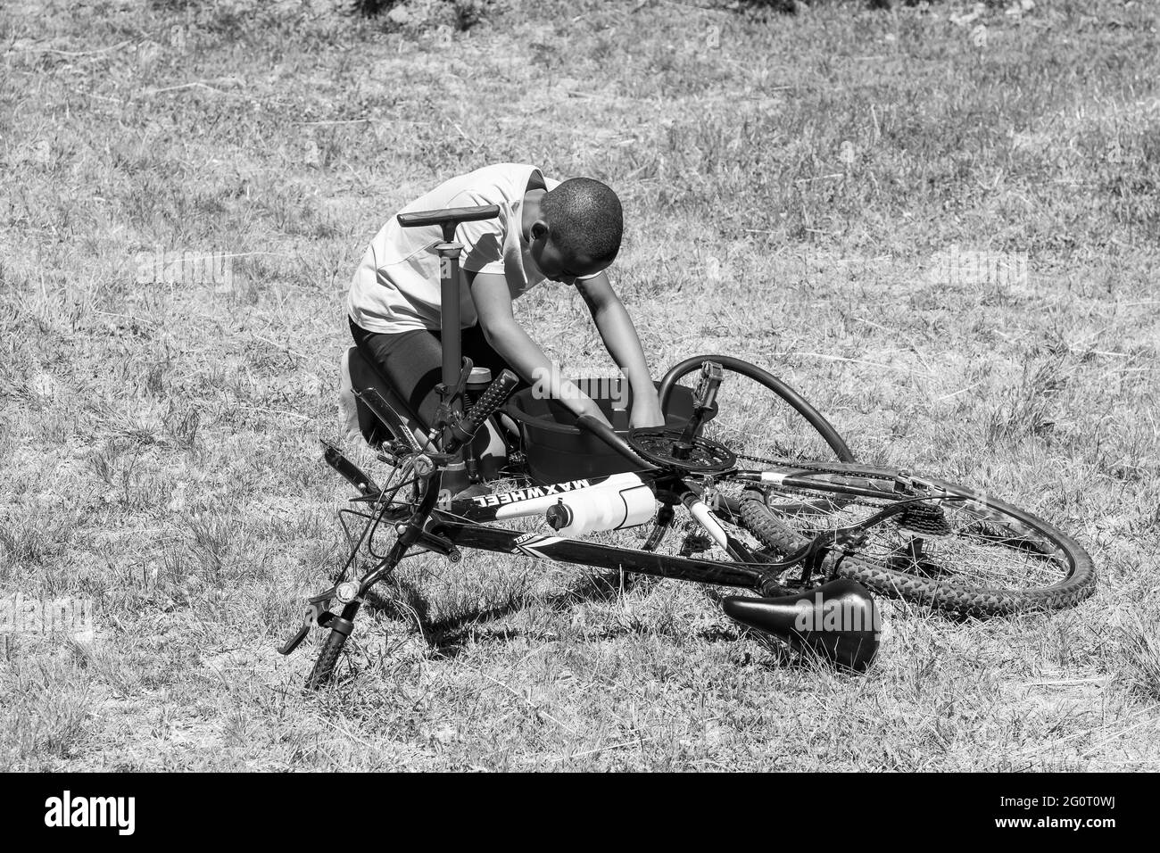 HARRISMITH, SÜDAFRIKA - 05. Jan 2021: Harrismith, Südafrika - 18 2012. Oktober: Afrikanische Kinder, die eine Punktion auf einem Fahrrad reparieren Stockfoto