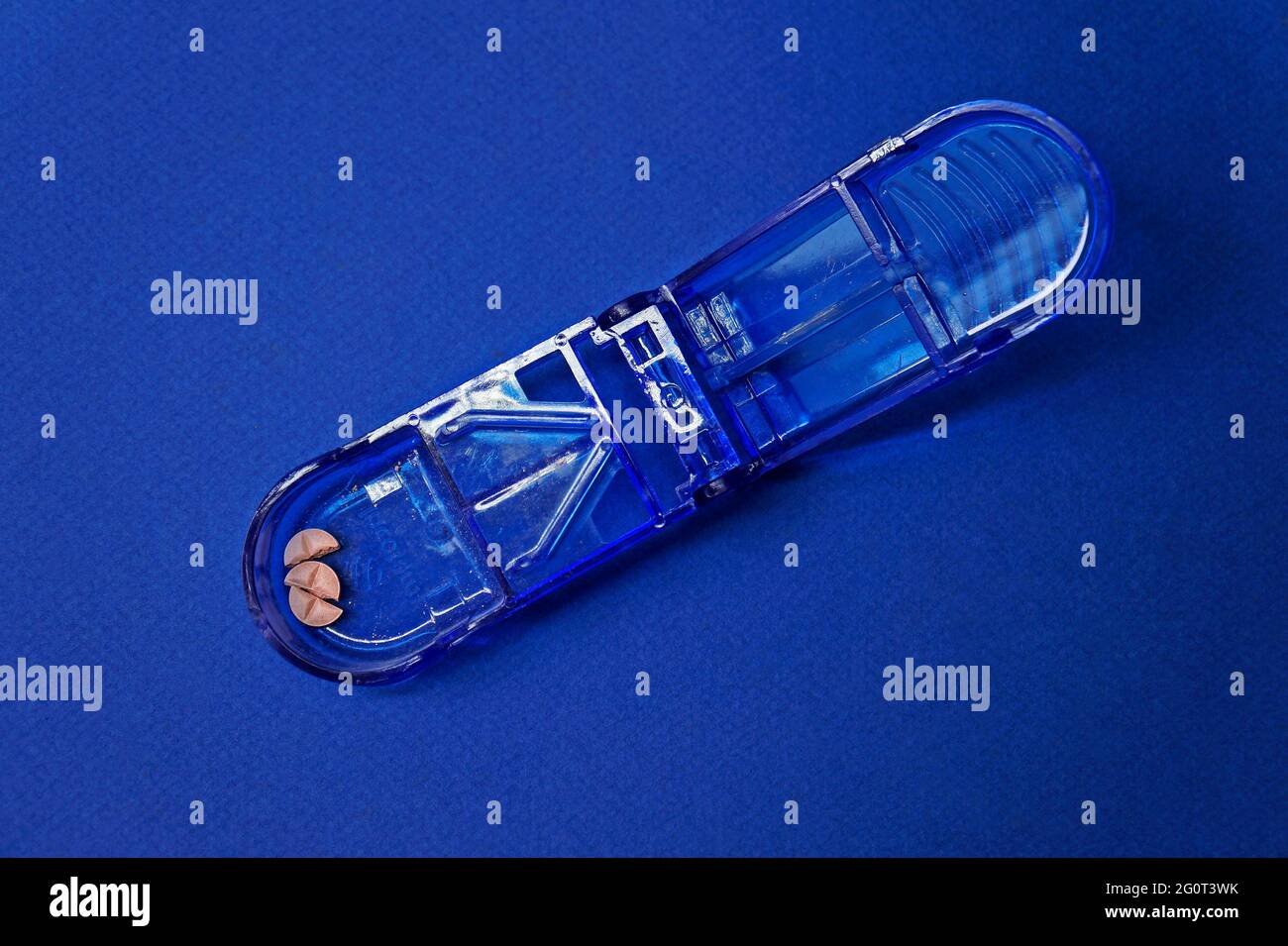 Blauer transparenter Pillenschneider auf blauem Hintergrund Stockfoto