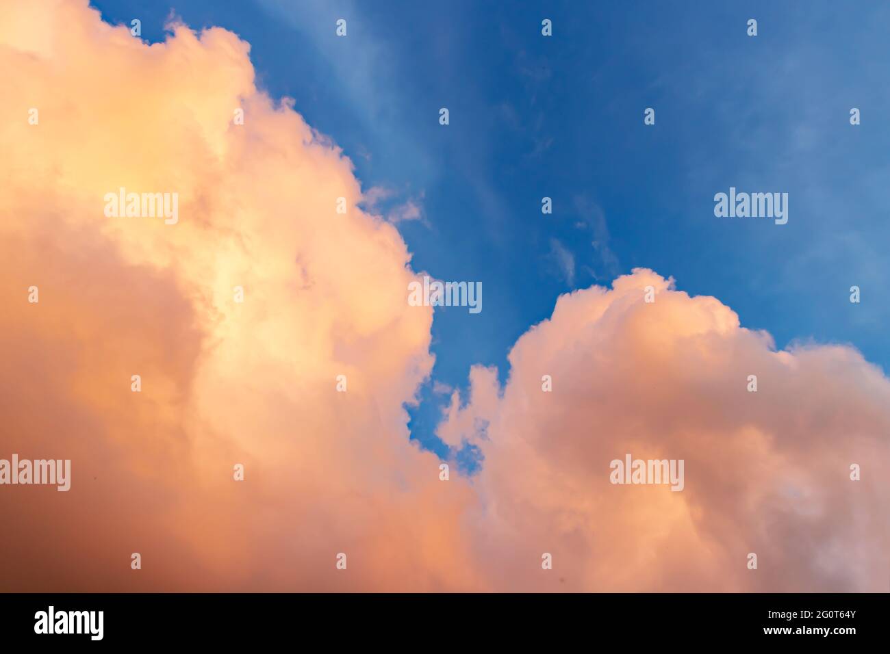 Wunderschöne Wolkenlandschaft - rosa-orange Wolken in den Strahlen der Sonne gegen den blauen Himmel Stockfoto