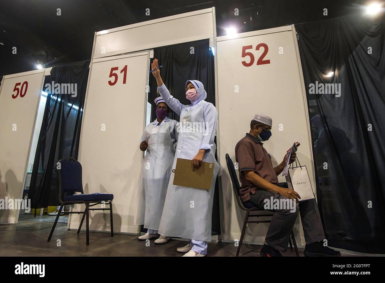 Kuala Lumpur, Malaysia. Mai 2021. Ein Mitarbeiter im Gesundheitsbereich geht auf das Malaysia International Trade & Exhibition Center an den nächsten Impfstoffempfänger.die malaysische Regierung wird mehrere neue Mega-Impfzentren einrichten, um die Impfkapazität von Covid-19 zu erhöhen und das überfüllte Problem zu lindern. Quelle: Vivian Lo/SOPA Images/ZUMA Wire/Alamy Live News Stockfoto