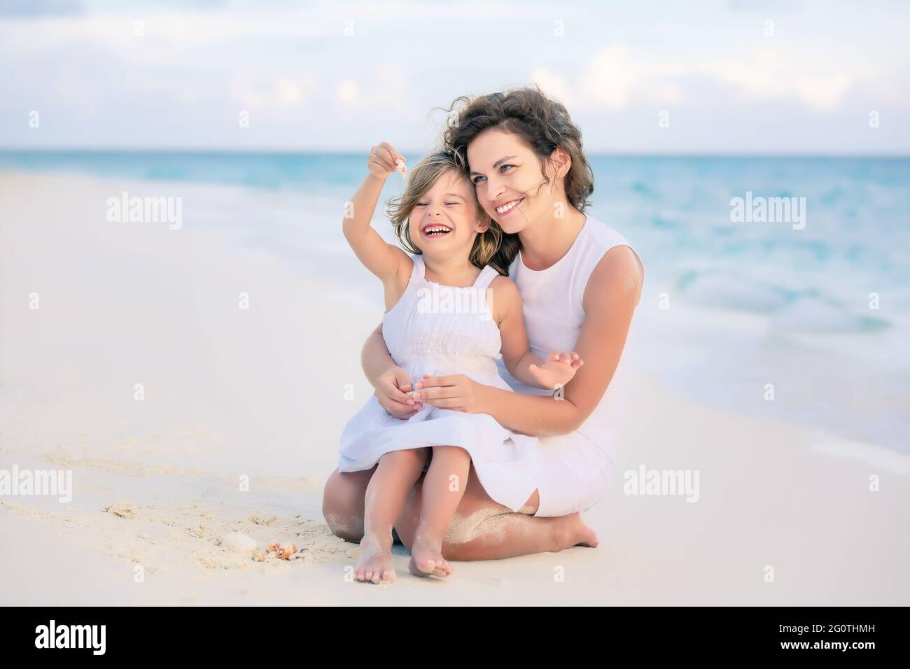 Mutter mit kleiner Tochter, die am Meeresstrand auf den Malediven spielt. Familie am Strand Konzept. Stockfoto