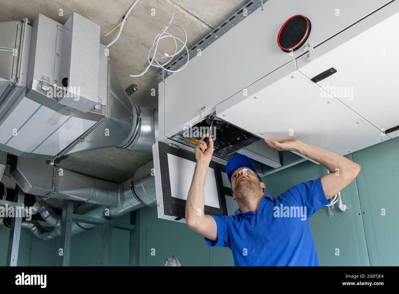 Ein hlk-Techniker installiert ein Abluftsystem mit Rückgewinnung der Wärmerückgewinnung Stockfoto
