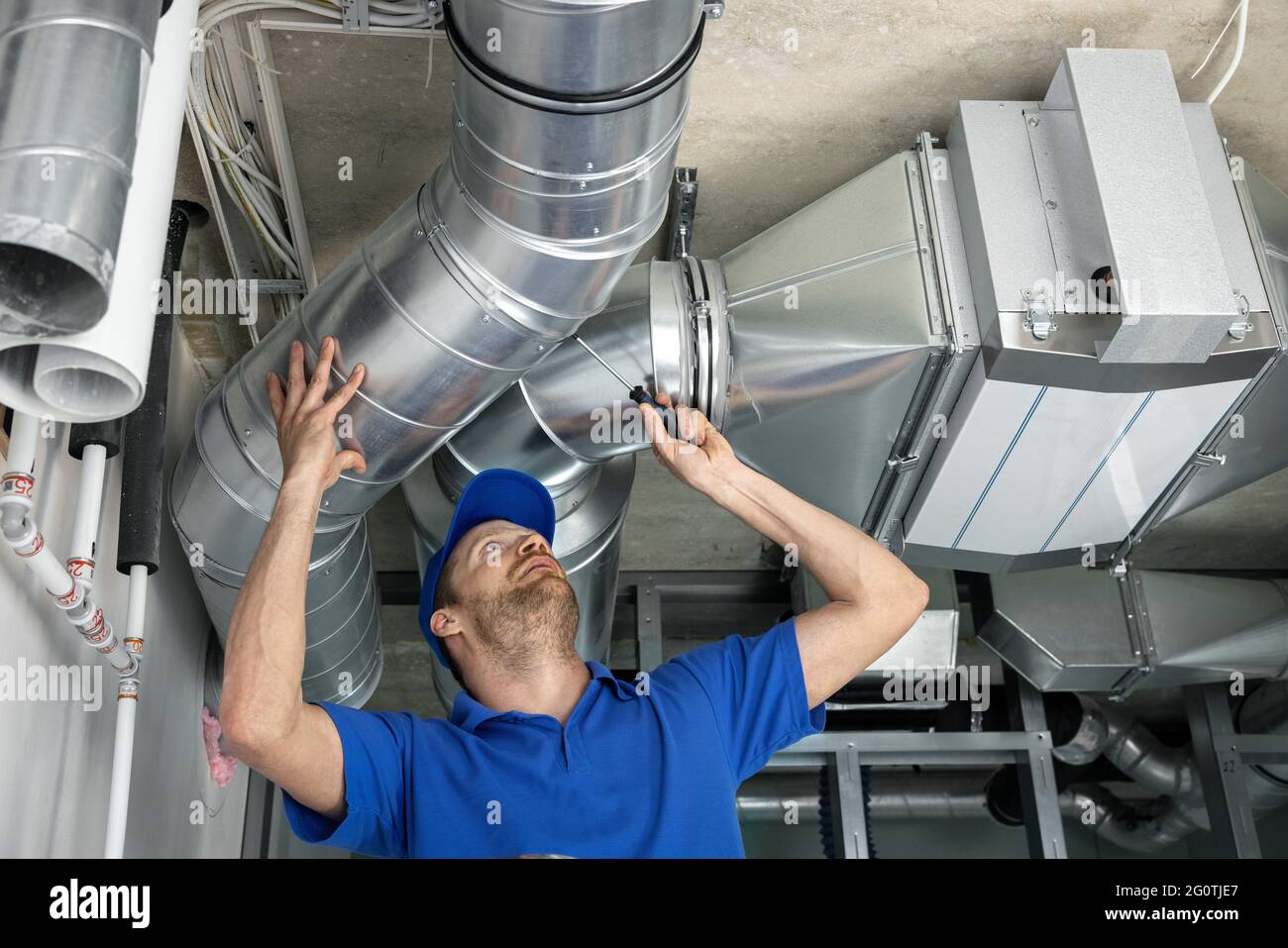 hlk-Dienstleistungen - Arbeiter installieren Rohrleitungssystem für Lüftung und Klimaanlage im Haus Stockfoto