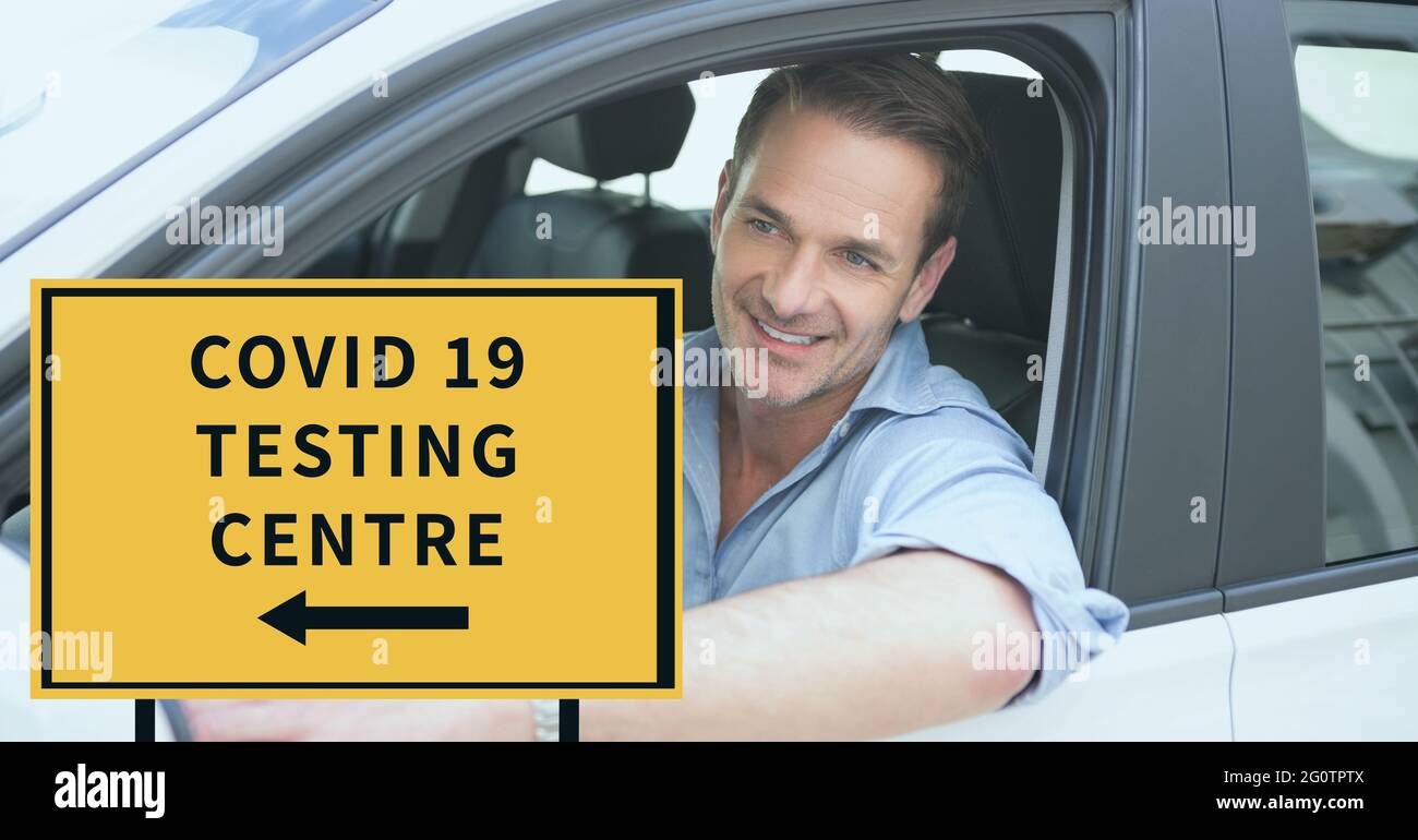 Zusammensetzung des covid 19 Testzentrum Text auf Schild über lächelnden kaukasischen männlichen Fahrer im Auto Stockfoto