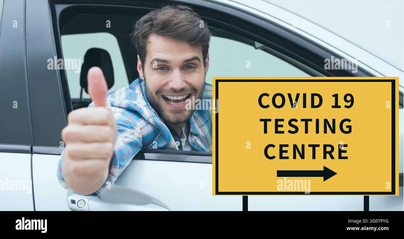 Zusammensetzung des covid 19 Testing Center Text auf Schild über lächelnden männlichen Fahrer im Auto mit Daumen nach oben Stockfoto