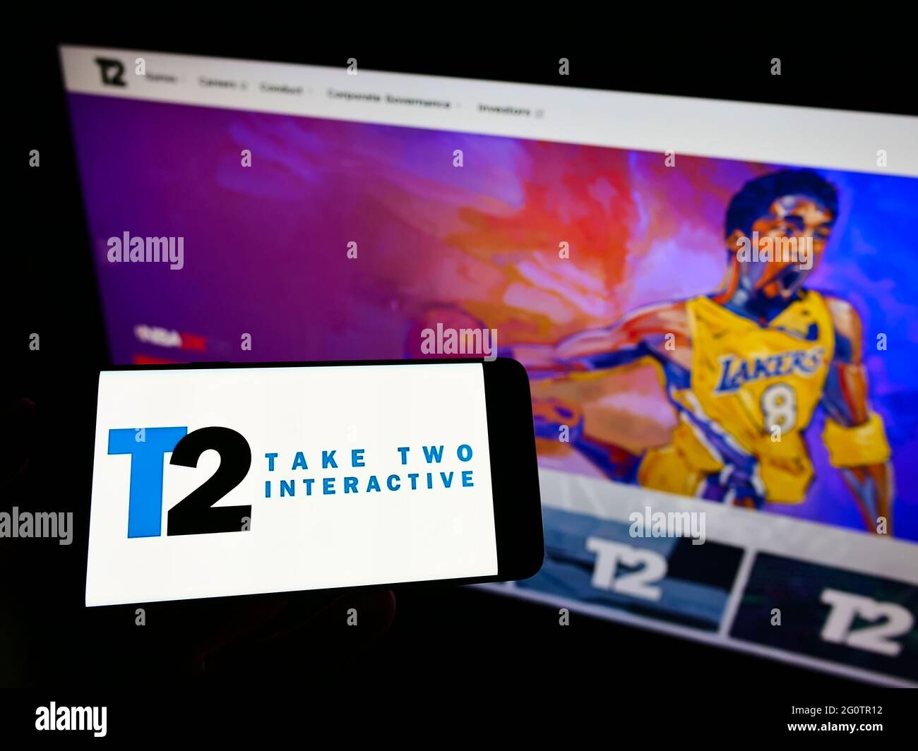Person, die Mobiltelefon mit dem Logo der Videospielfirma Take-Two Interactive Software Inc. Auf dem Bildschirm vor der Webseite hält. Konzentrieren Sie sich auf die Telefonanzeige. Stockfoto