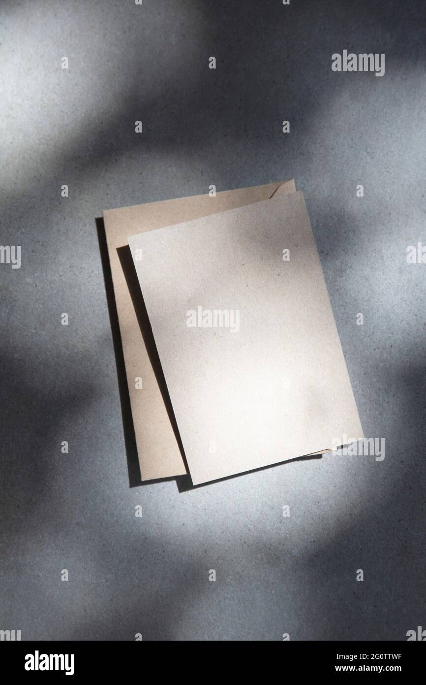 Weiße braune Einladung oder Postkarte mit Umschlag unter strahltem Sonnenlicht Stockfoto