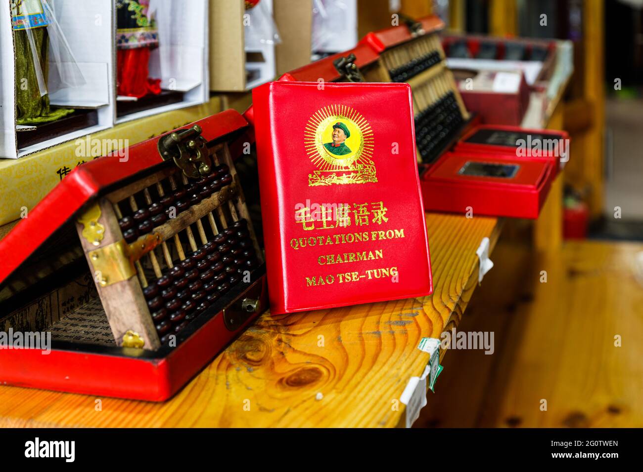Ein Buch, bekannt als die Mao-Bibel, mit den Zitaten des Vorsitzenden Mao Tse-Tung in rotem Einband, Porträt und Goldschrift, die in einem Geschäft auf einem Holzschal ausgestellt sind Stockfoto