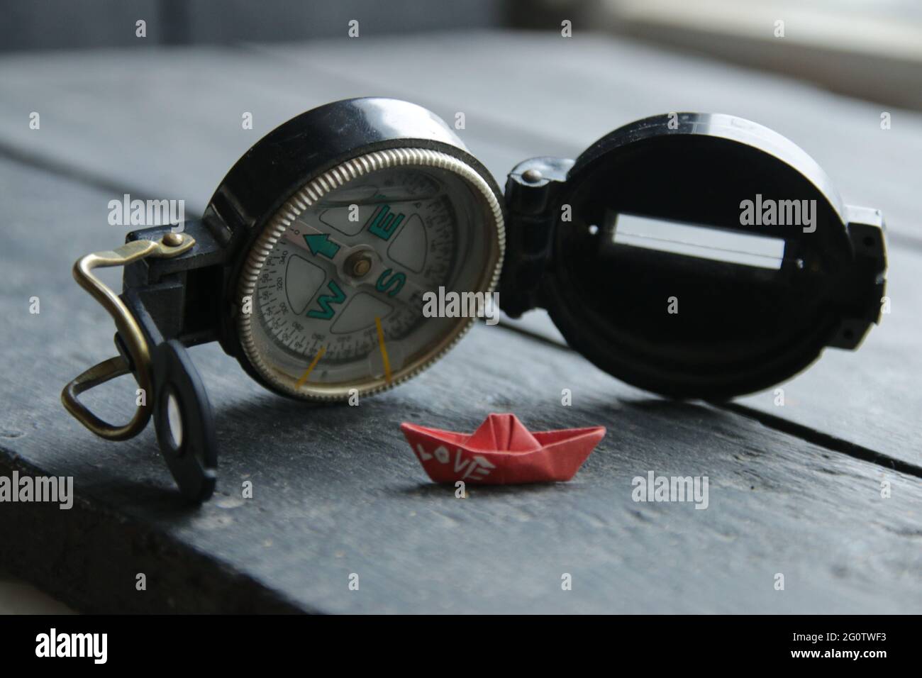 Suche nach Liebeskonzept. Navigationskompass und ein Papierboot. Stockfoto