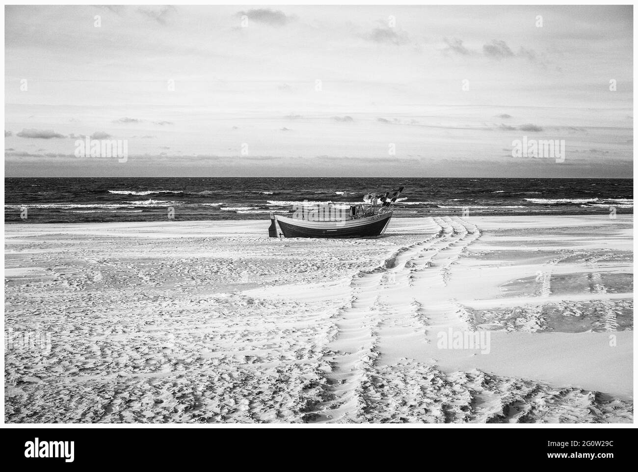 Fischerboote an der Küste des Osstsees am Strand in Polen in melancholischem Schwarz-Weiß-Look. Strand an der Ostsee mit Fischerbooten. Stockfoto