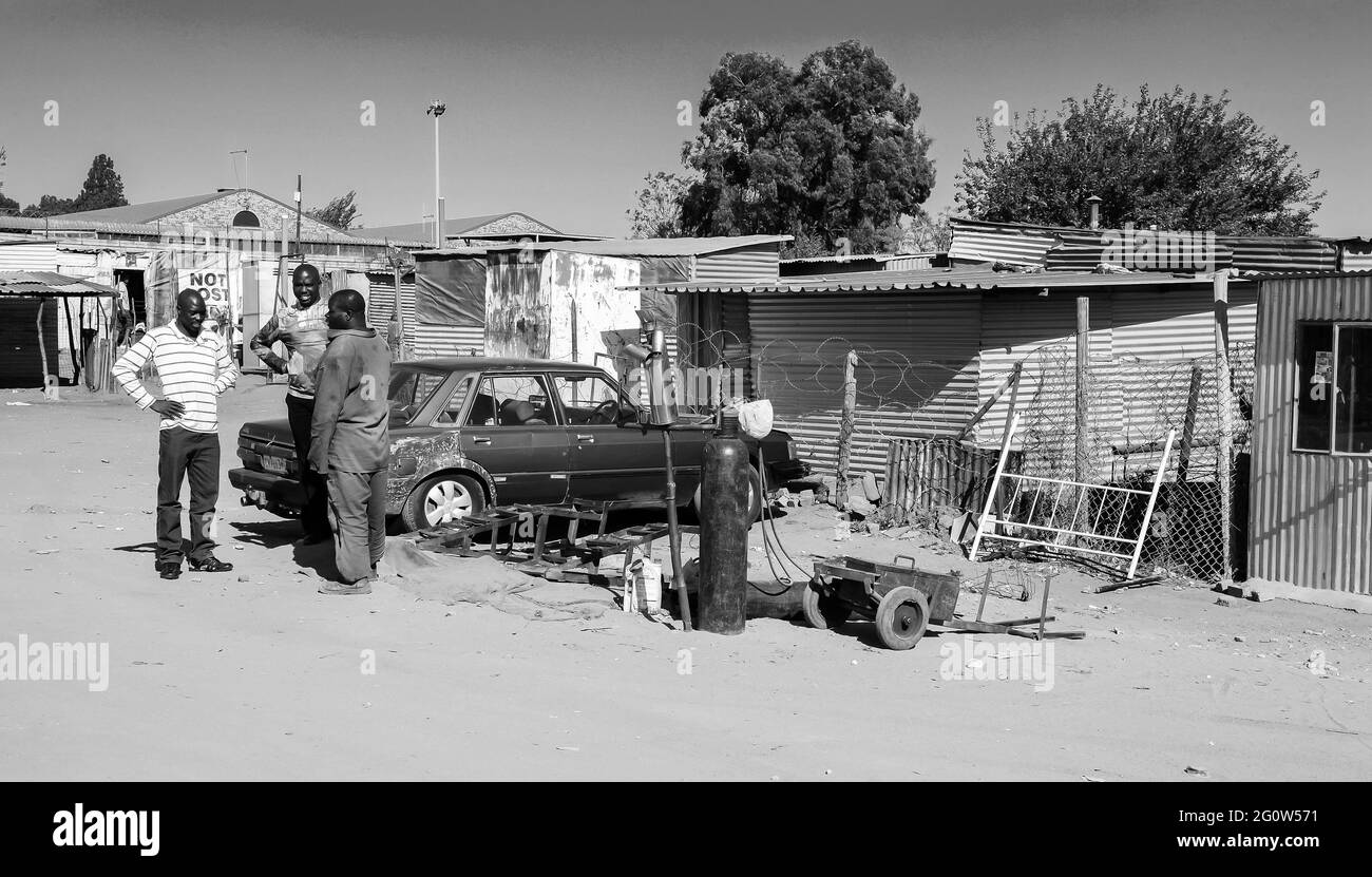 JOHANNESBURG, SÜDAFRIKA - 05. Januar 2021: Johannesburg, Südafrika, 11. September 2011, Kleiner informeller Straßenhändler, der die Auspuffanlagen von Fahrzeugen auf der Straße repariert Stockfoto