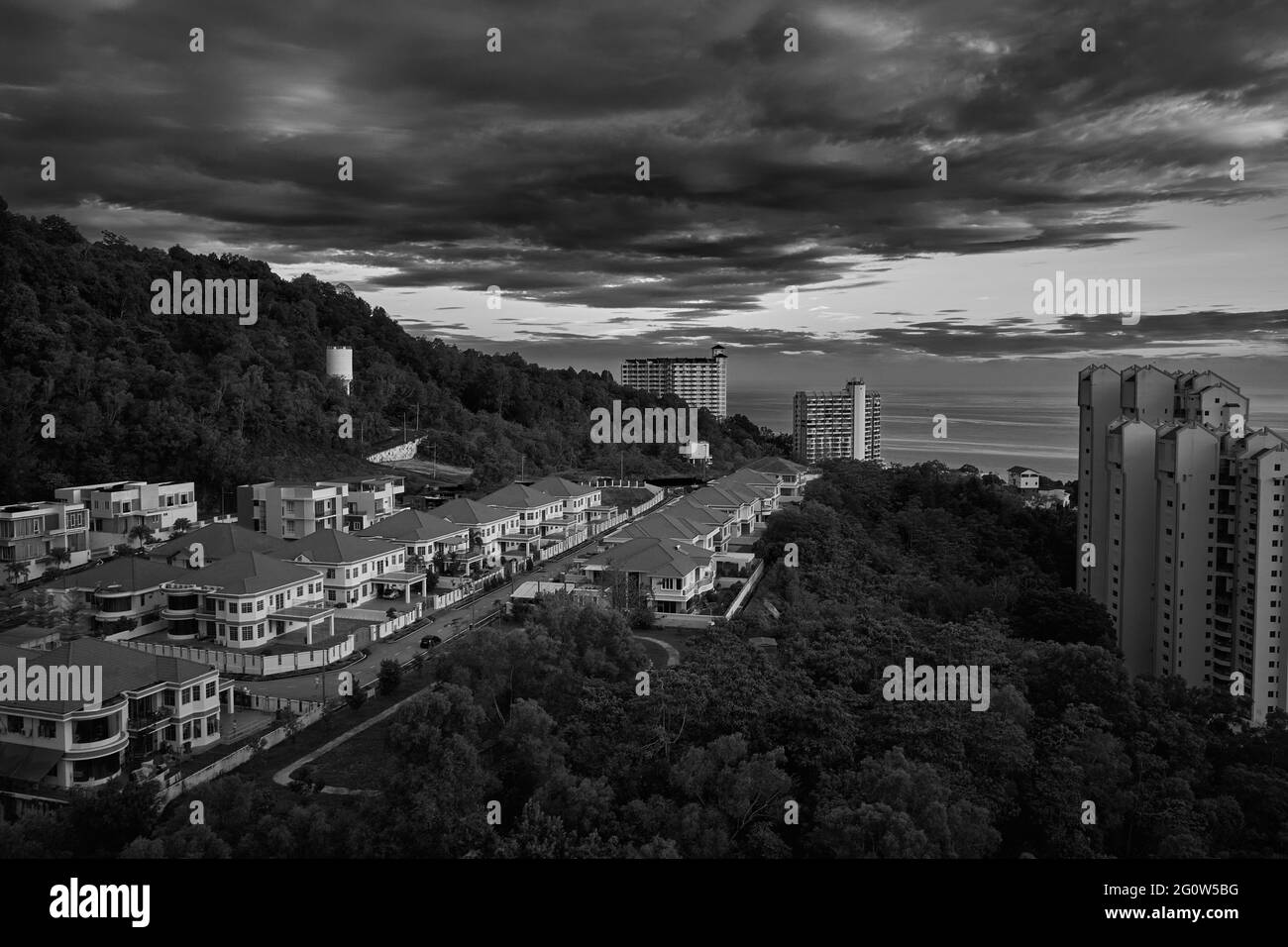 Blick auf den Dschungel, das Meer, die umliegenden Häuser mit einem launisch bewölkten Himmel im Hintergrund aus dem zwanzigsten Stock einer Wohnung in Penang, Malaysia Stockfoto