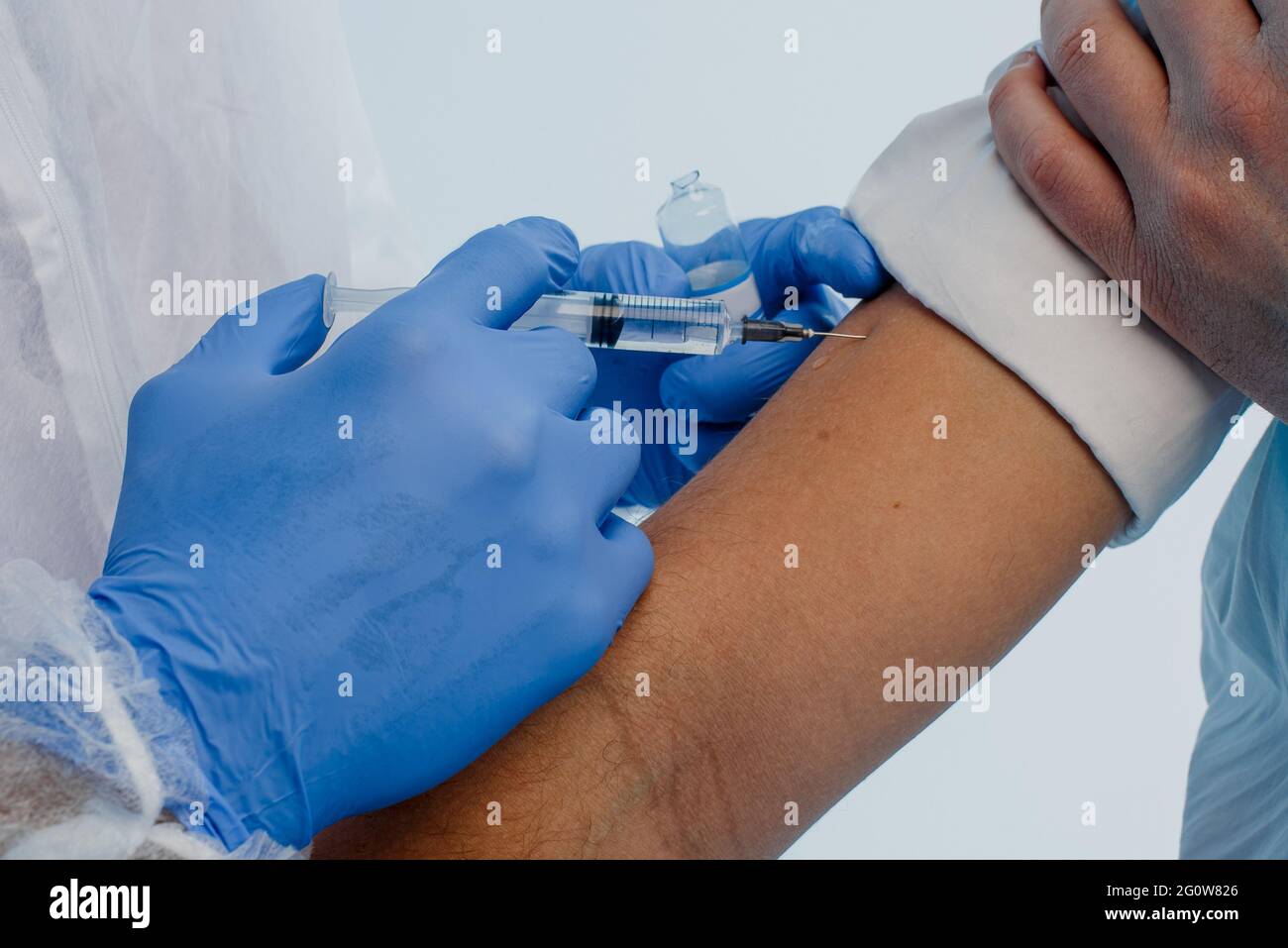 Arzt injiziert COVID-19-Impfstoff an männlichen Patienten Stockfoto