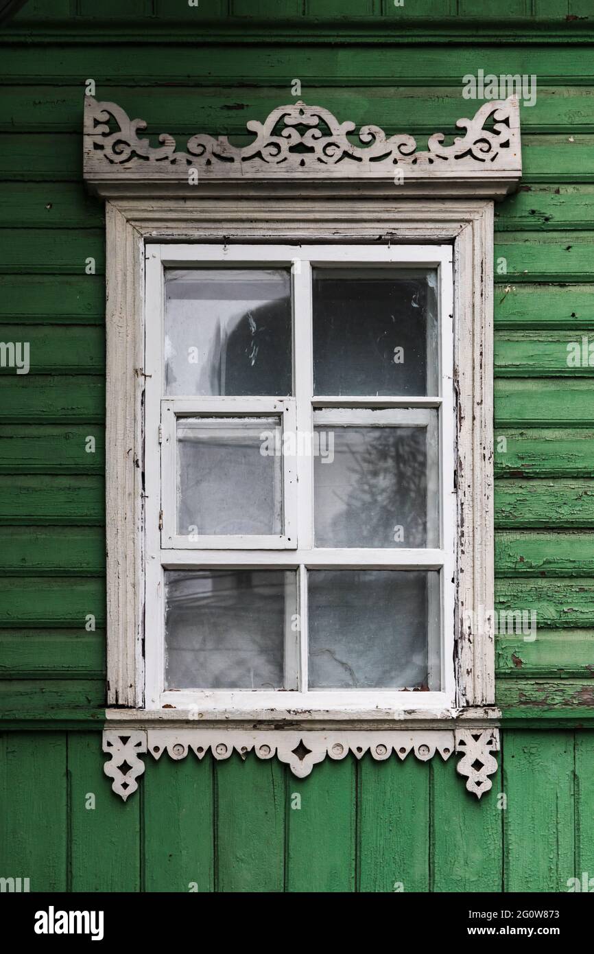 Fenster in weißem dekorativem Rahmen in einer alten ländlichen Holzhauswand, architektonische Hintergrundstruktur Stockfoto