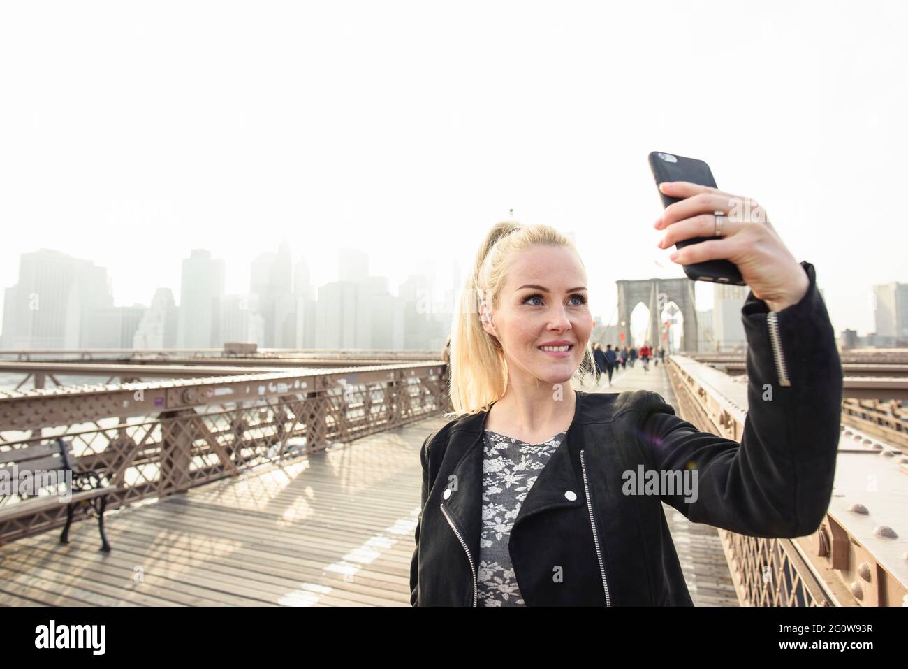 Glückliche Frau, die Selfie auf der Fußgängerüberführung in Megapolis macht Stockfoto