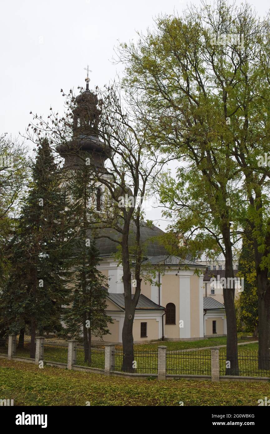 Römisch-katholische Kirche St. Nikolaus, Zamosc. Alte katholische Kirche umgeben von Herbstbäumen, Landschaft. Stockfoto