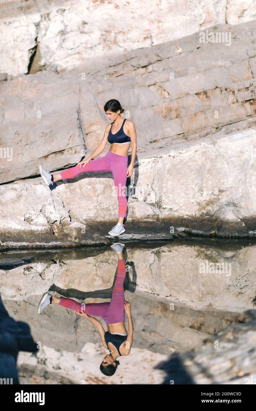 Schöne Frau macht Bewegung in der Natur, auf der Klippe in der Nähe des Meeres. Gesundes Lifestyle-Konzept. Stockfoto