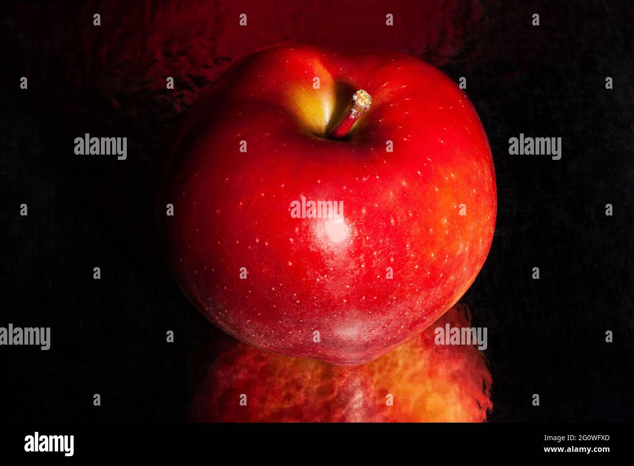 Roter köstlicher Apfel auf schwarzem reflektierendem Hintergrund Stockfoto