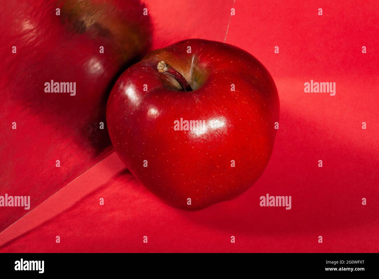 Verspiegelter roter köstlicher Apfel auf rotem Hintergrund Stockfoto