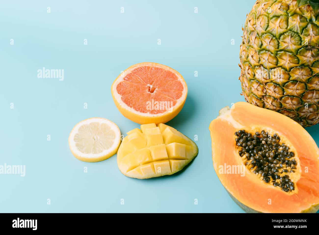 Frische exotische Früchte auf blauem Hintergrund - Papaya, Mango, Ananas, Zitrone, Grapefruit. Sommerkonzept und gesunde Ernährung. Platz kopieren Stockfoto