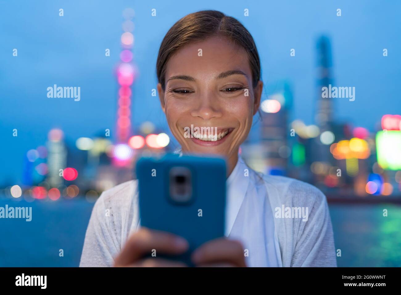 Asiatische Frau SMS auf Smartphone in der Stadt in der Nacht Stockfoto