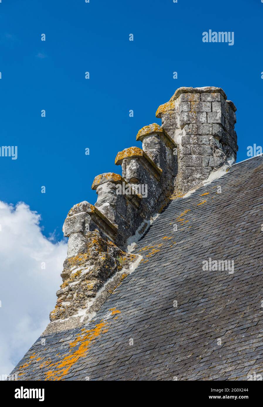 Detail eines steil abfallenden alten Daches und Steinkamins in Chatillon-sur-Indre, Indre (36), Frankreich. Stockfoto