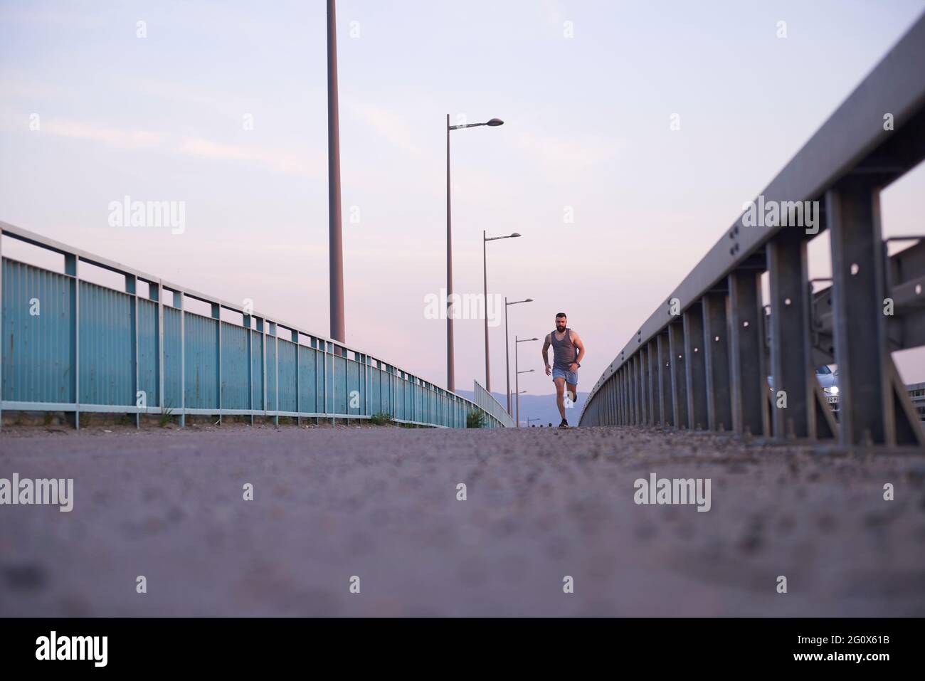 Ein Mann, der während seines morgendlichen Workouts über eine Brücke läuft Stockfoto