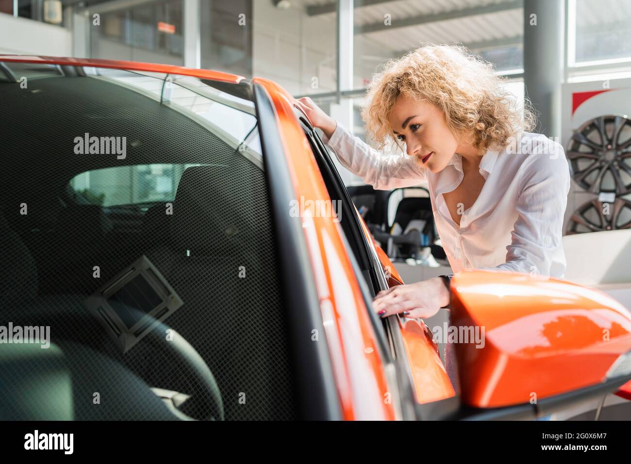 Lockige Frau schaut Auto auf den Händler Stockfotografie - Alamy