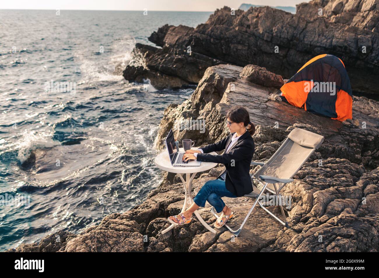 Geschäftsfrau, die vom Strand aus arbeitet. „Arbeiten aus der Ferne“-Konzept. Freiberufler reisen und arbeiten online. Stockfoto