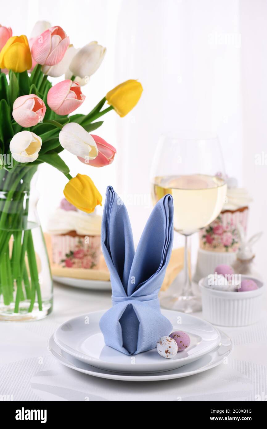 Eine Serviette, die in Form eines Hasen (Hasen) gefaltet ist, das Konzept, zu Ehren des Osterfestes einen festlichen Tisch zu legen. Stockfoto