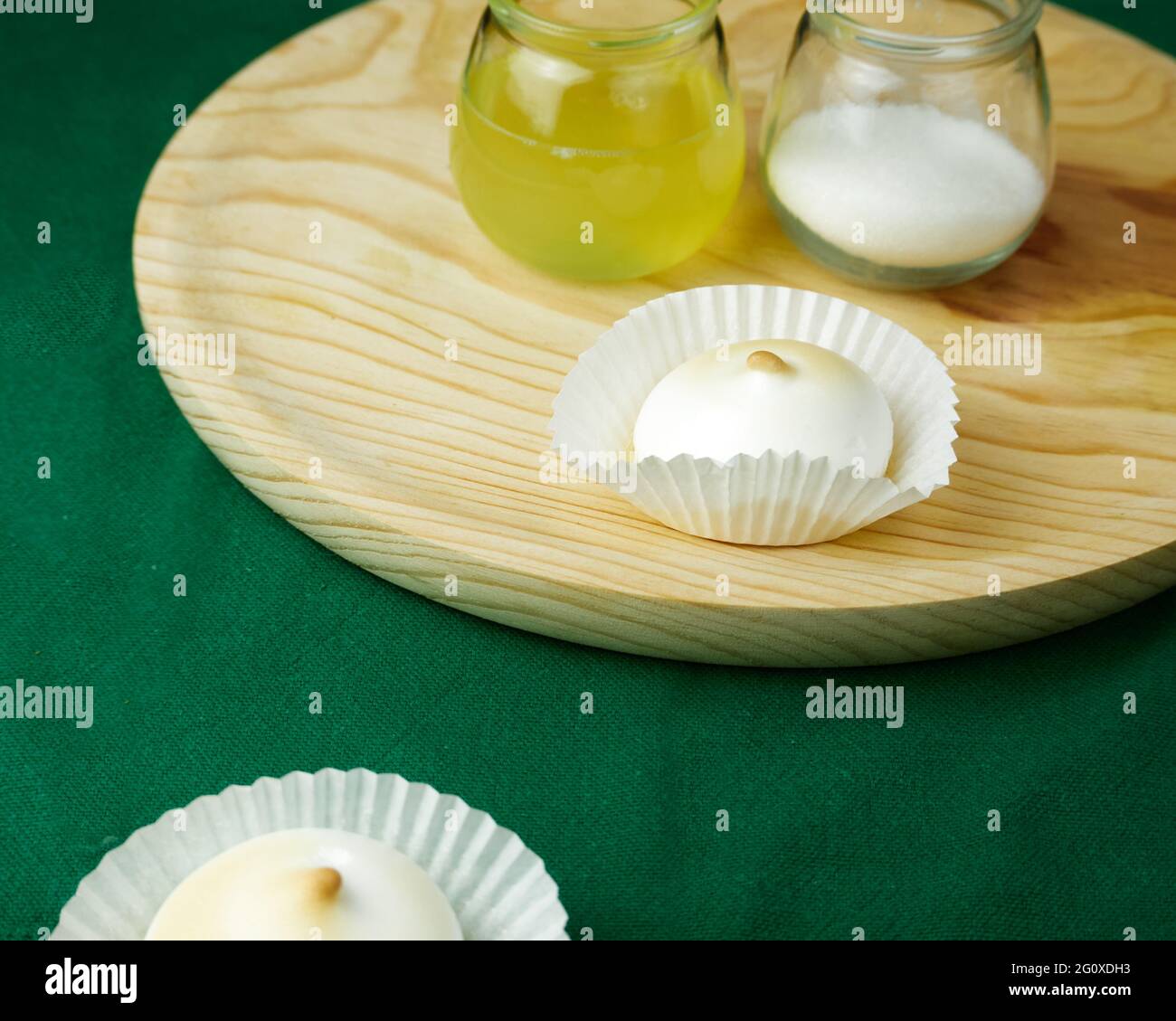 Mehrere französische Desserts Meringue zu einer Silikonform Formen auf grüner Tischdecke und seine Zutaten auf einem runden Holzteller Stockfoto