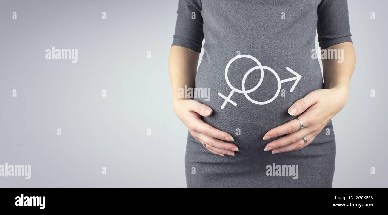 Nahaufnahme des Bauches einer Schwangeren mit Hologramm-Symbol für das männliche und weibliche Geschlecht. Schwangerschaft, Mutterschaftskonzept. Stockfoto