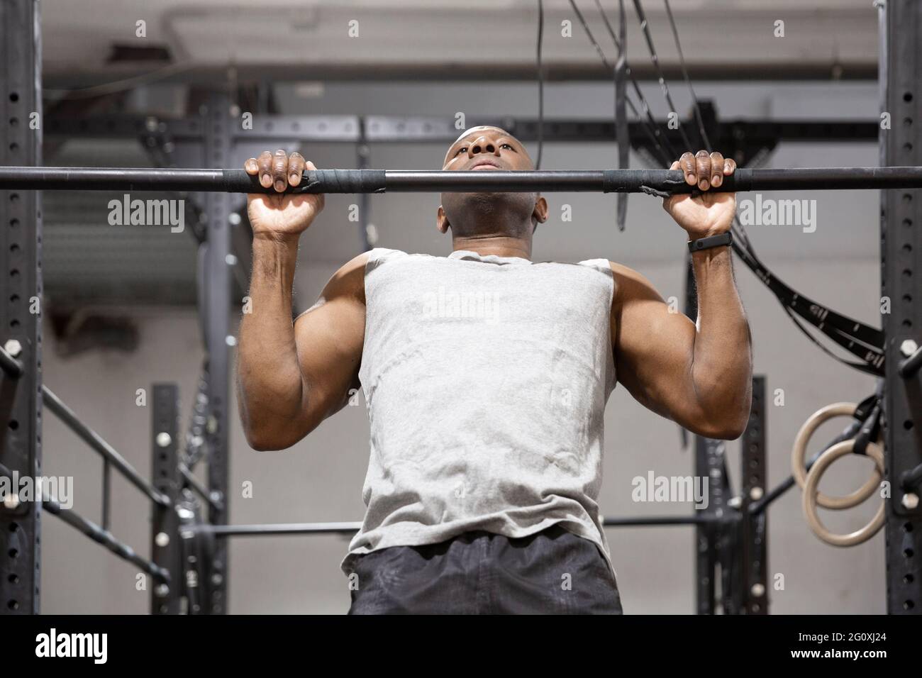 Afroamerikanischer Sportler, der auf einer festen Stange Sport macht. Fitnesstraining im Fitnessstudio. Stockfoto
