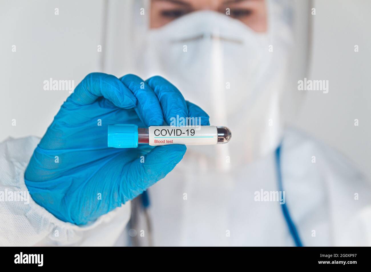 Ärztin oder Krankenschwester im Schutzanzug mit positivem blo Stockfoto