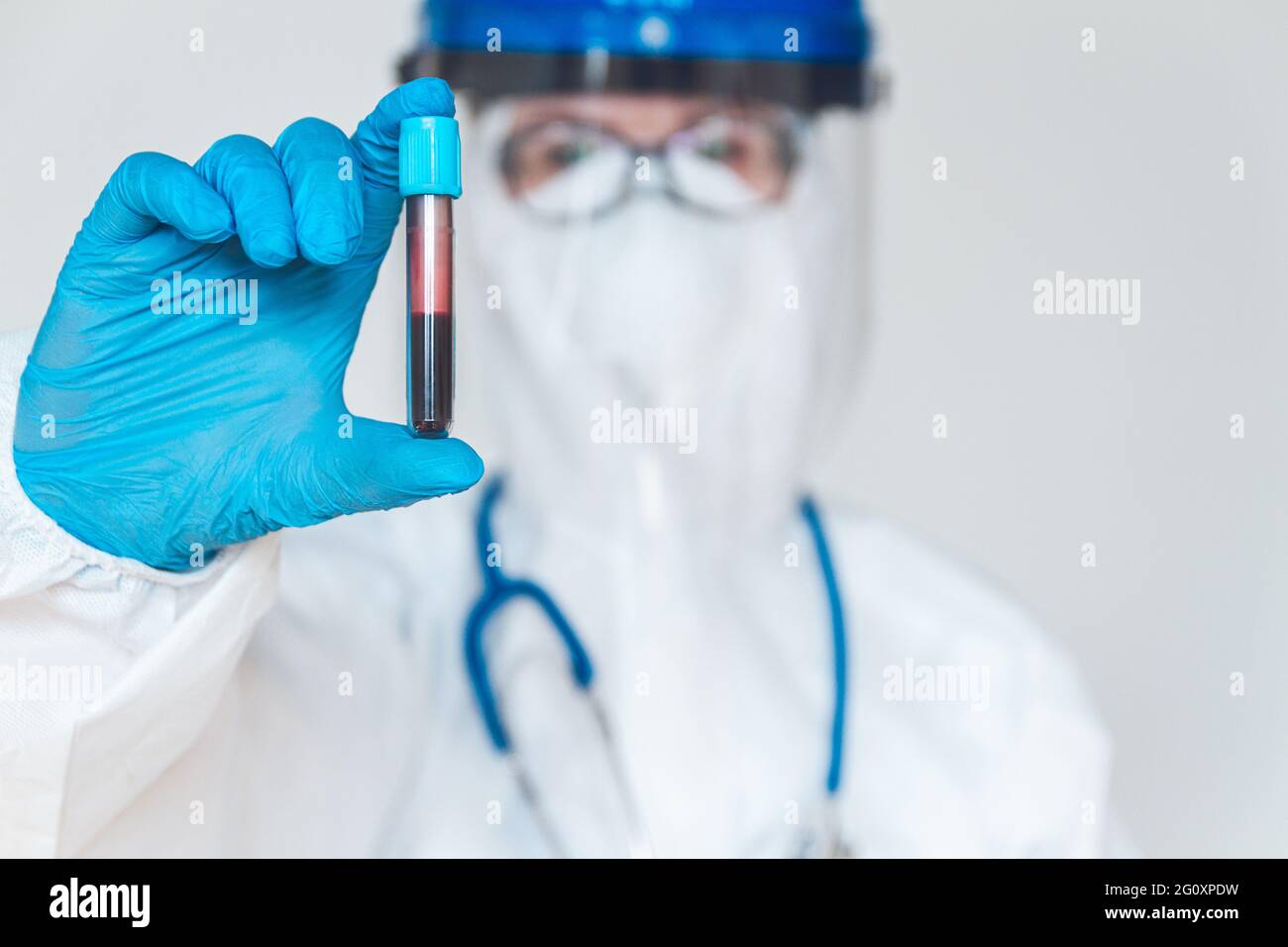 Ärztin oder Krankenschwester im Schutzanzug mit positivem blo Stockfoto