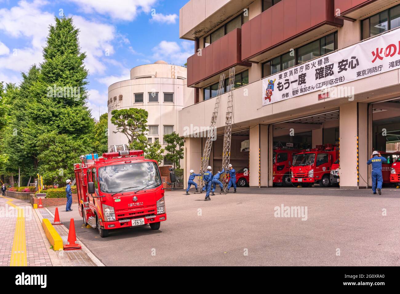 tokio, japan - 11 2020. juni: Japanische rote Feuerwehrautos parkten in der Feuerwache von Tazinogawa mit Feuerwehrhelfern, die Schutzhelme tragen Stockfoto