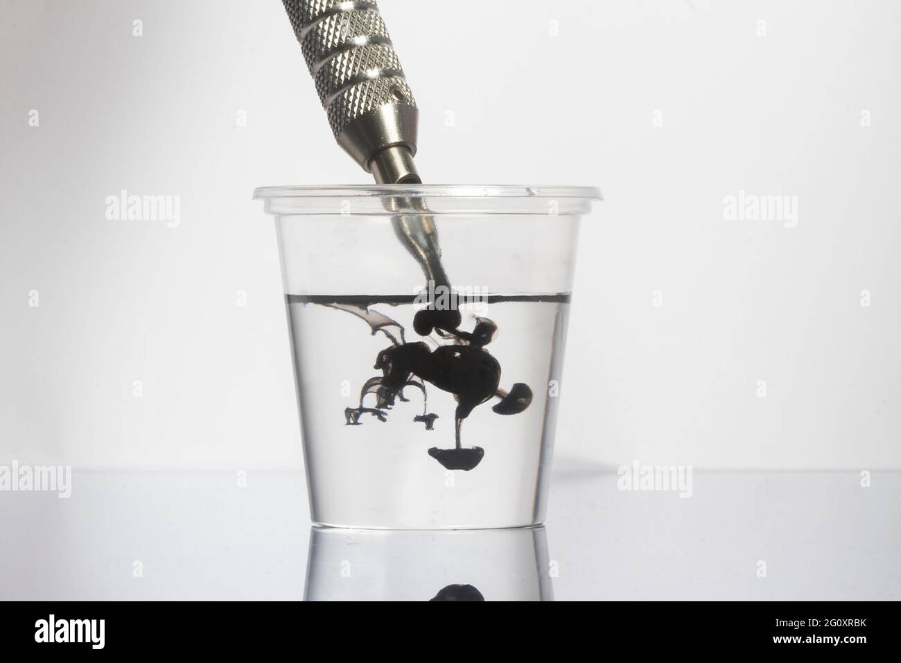 Tattoo Maschine schwarze Tintennadeln mit sauberem Wasser in klarem Glas reinigen Stockfoto