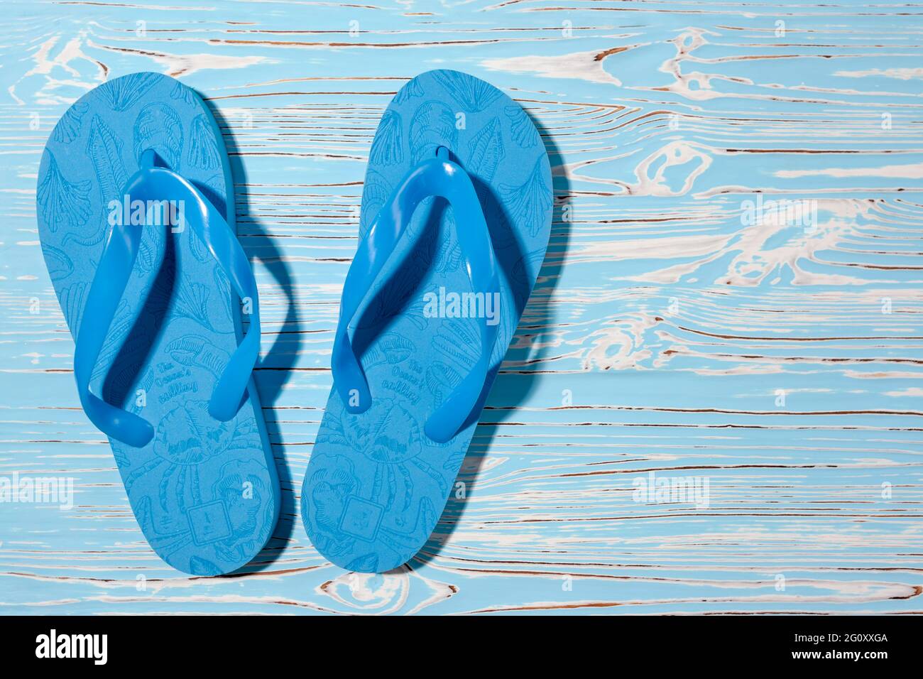 Blaue Gummi-Strandflipflops auf blauem Holzhintergrund, Platz für Text Stockfoto