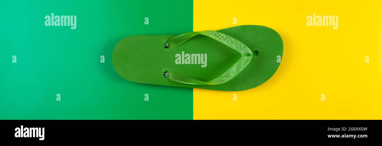Grüner Gummiflip Flop auf gelbgrünem Hintergrund, Banner Stockfoto