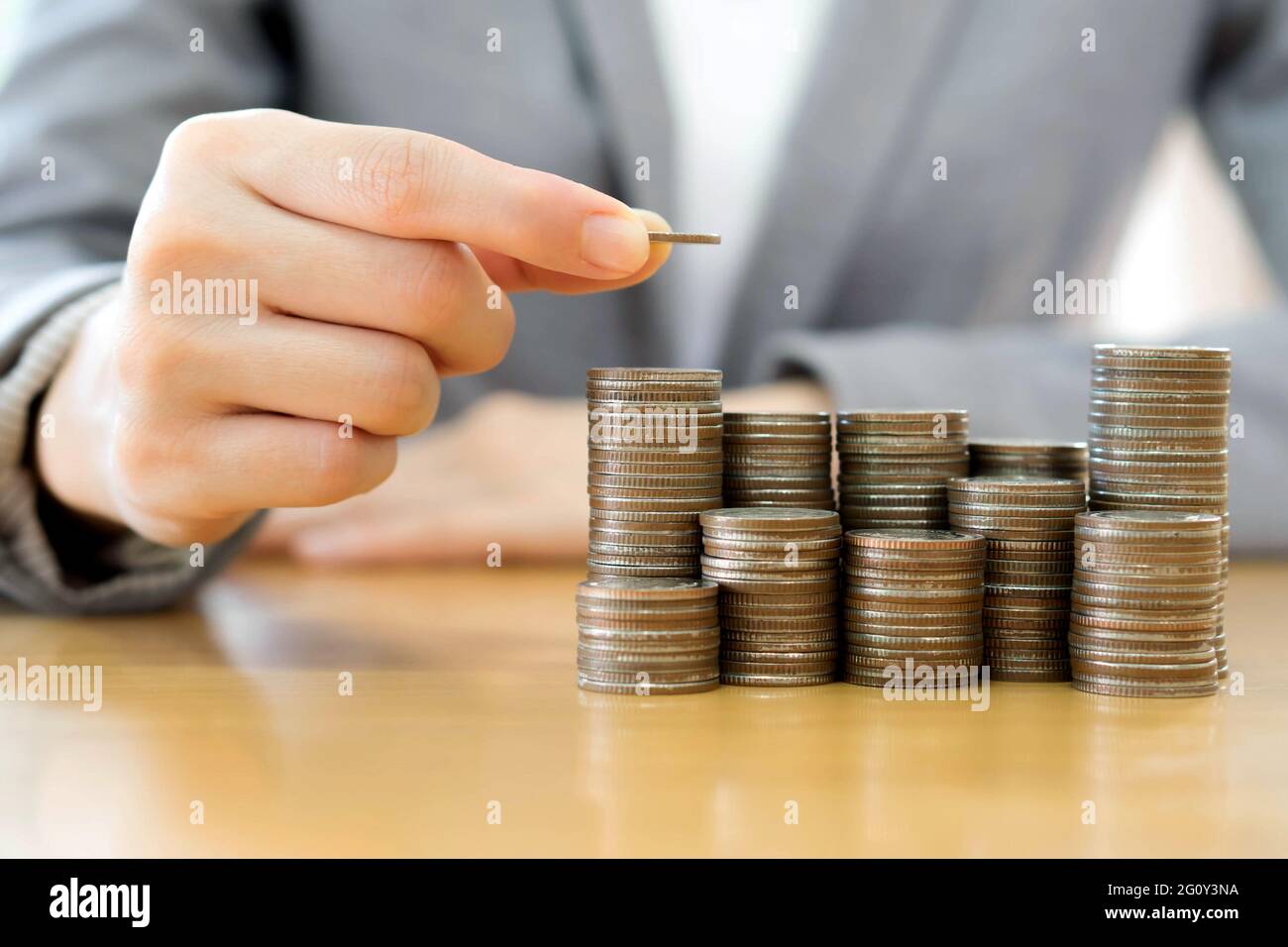 Geschäftsfrau legte Münzen zu Stapel von Münzen Stockfoto